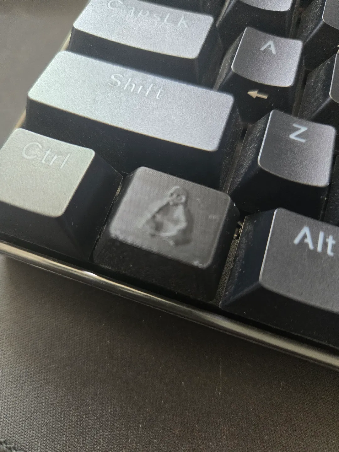 A Tux keycap that looks like a time-weathered relief