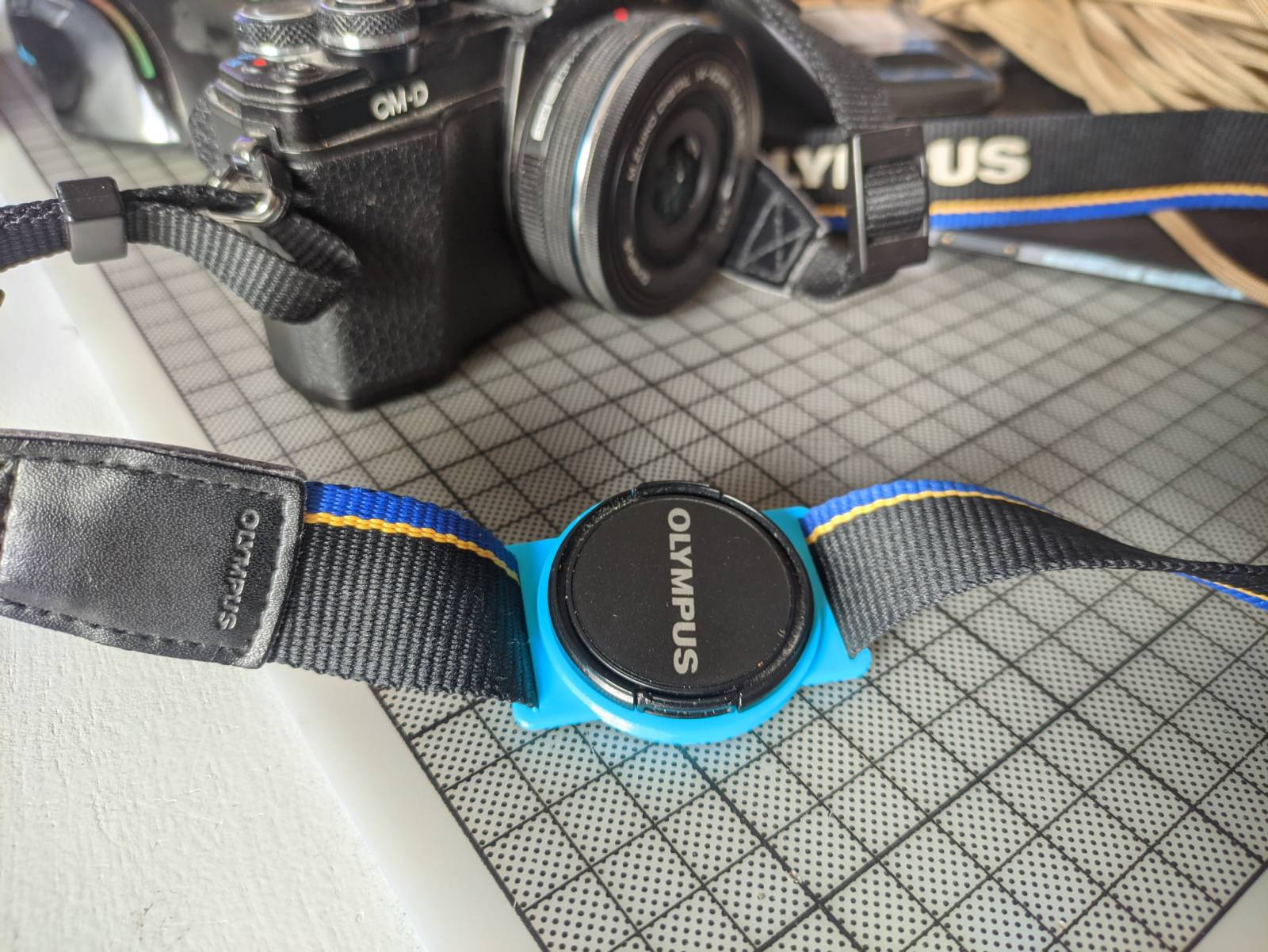 Camera lens cap strap holder