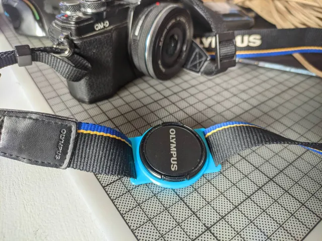 Camera lens cap strap holder