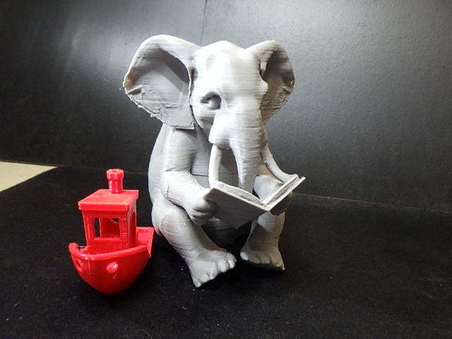 Elephant sitting down reading a book.