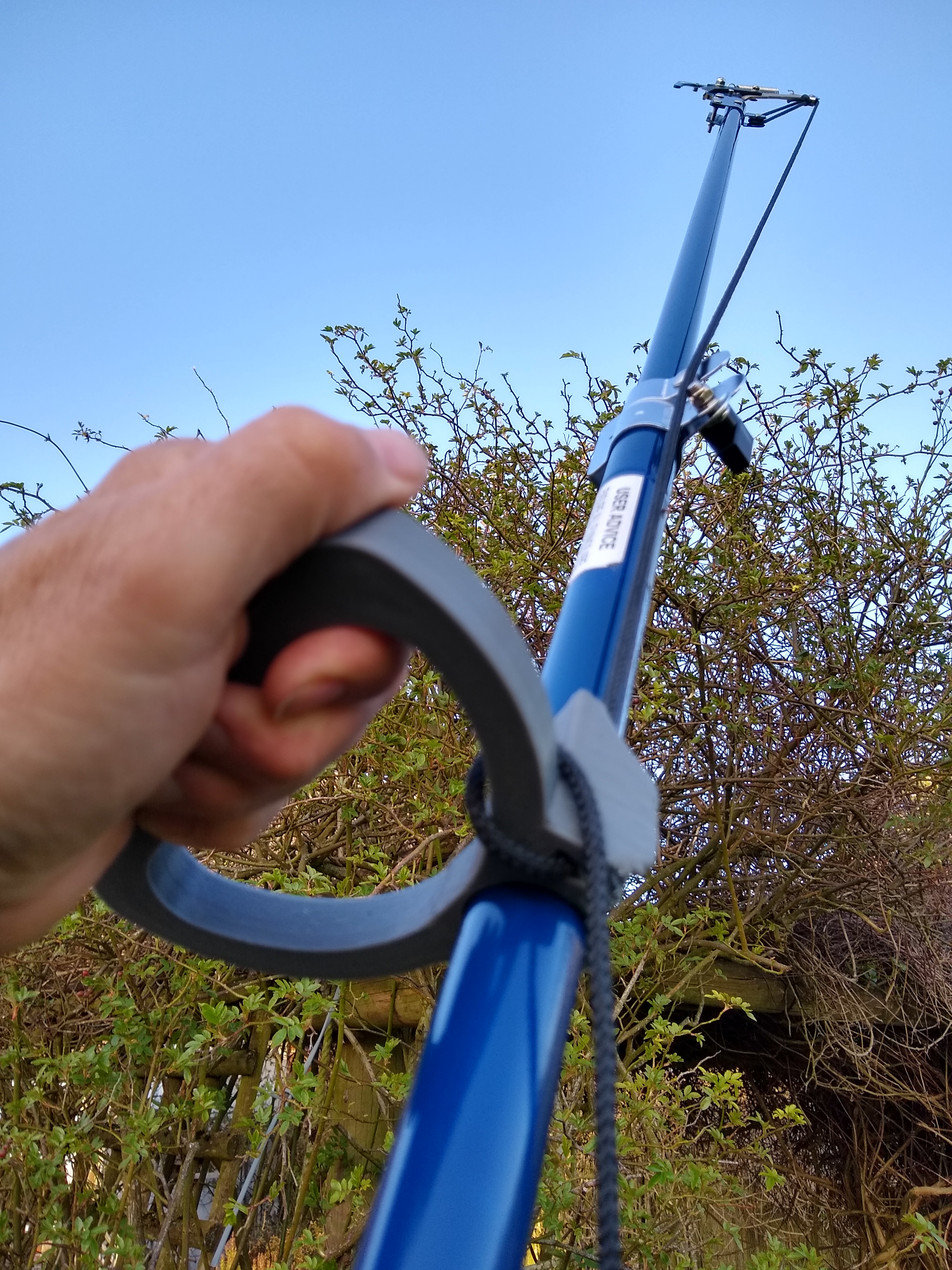 Device to hold and snip a long handled pruner