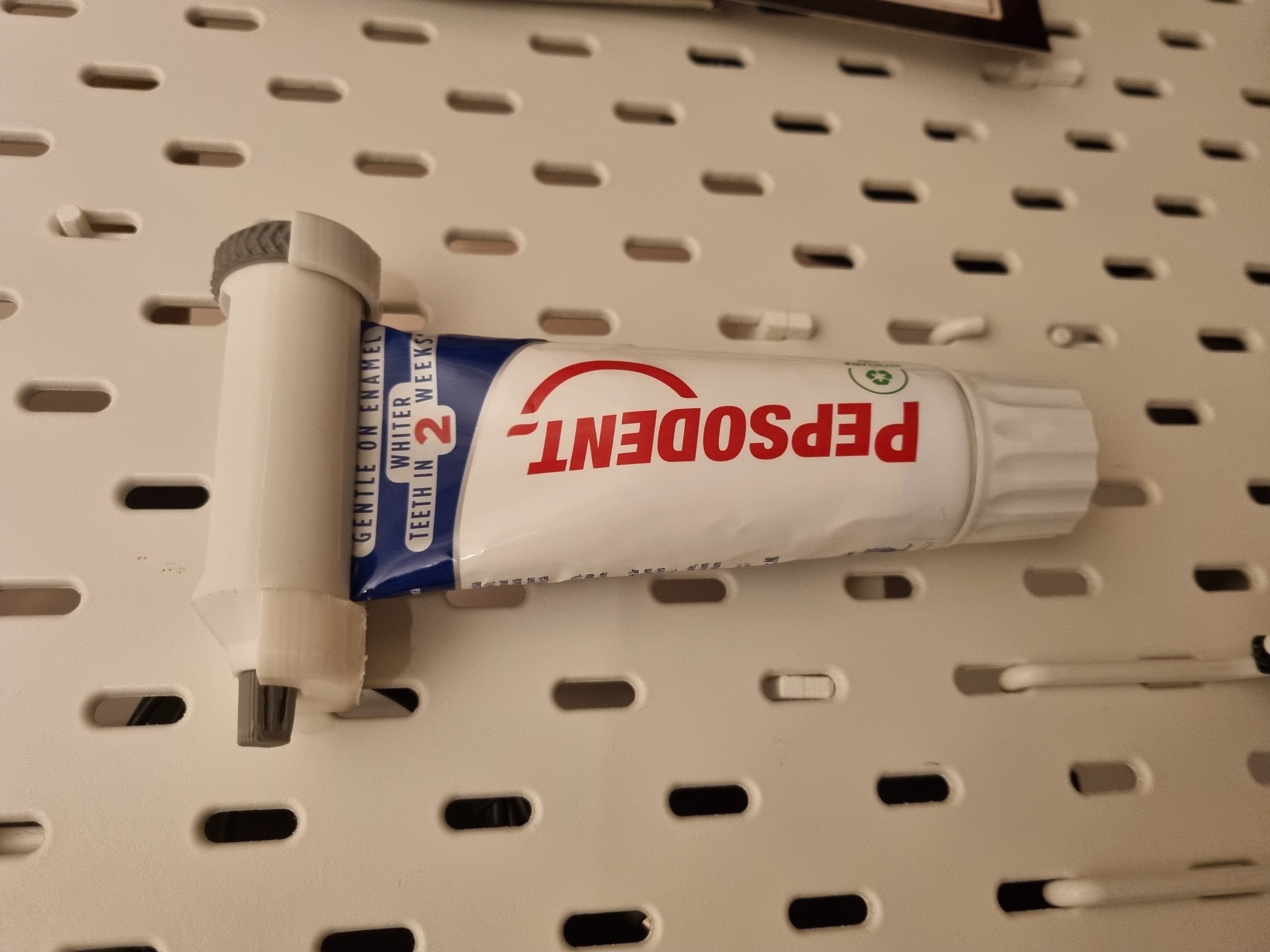 Skadis toothpaste holder for ratchet toothpaste tube squeezer