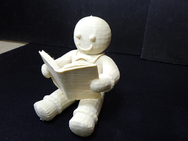 A gingerbread man reading a book sitting down.