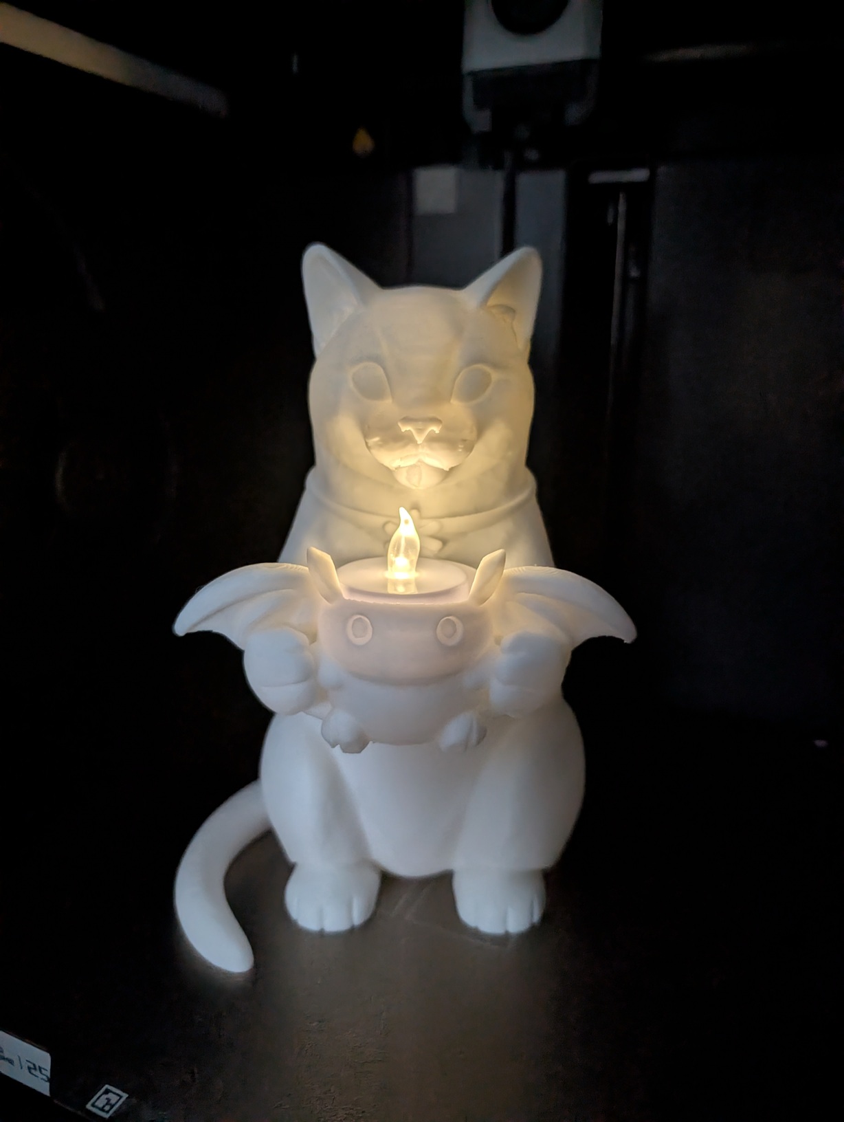Cat statue holding a baby creature tea light.