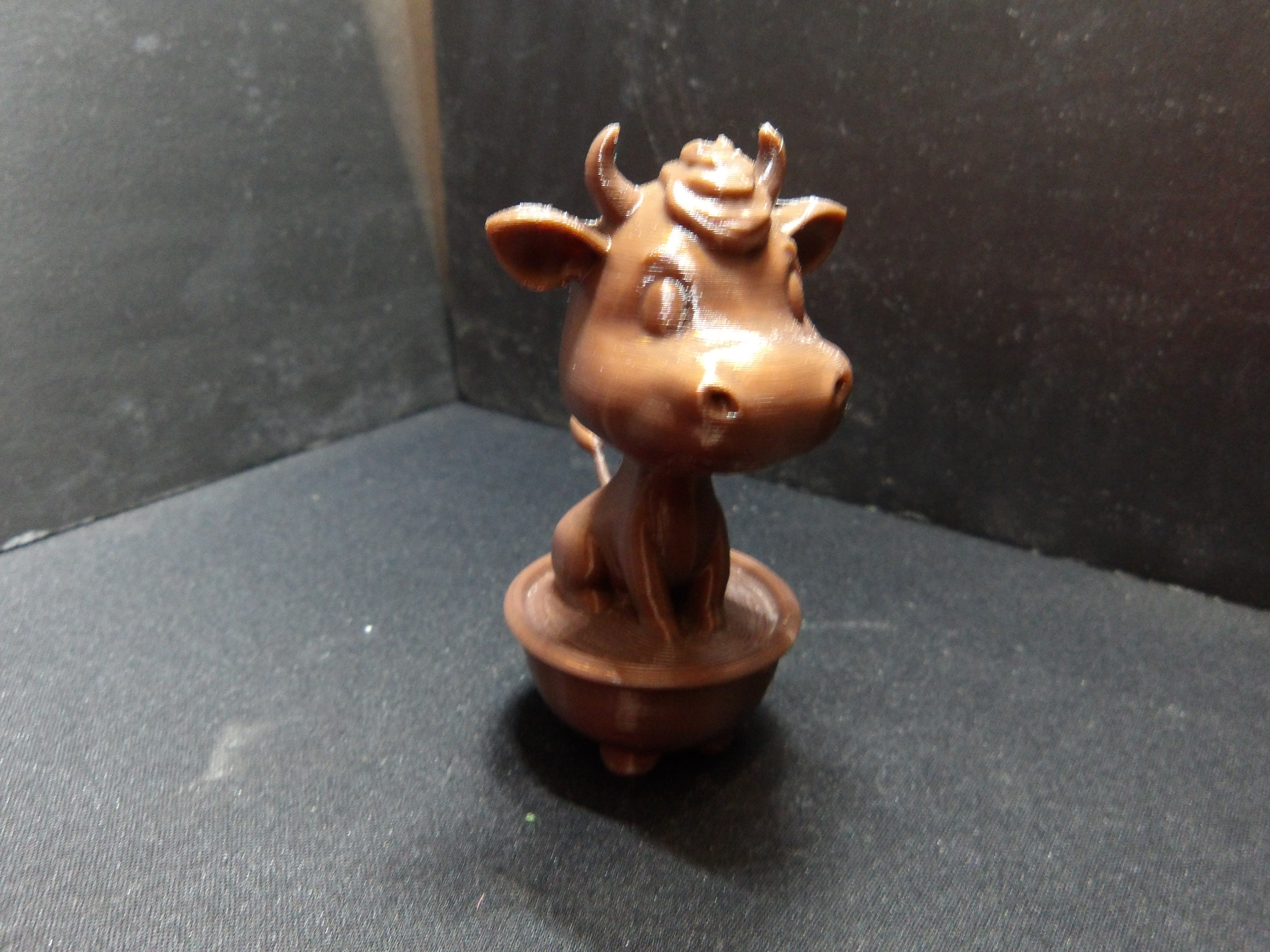 A cute cow sitting in a flower pot.