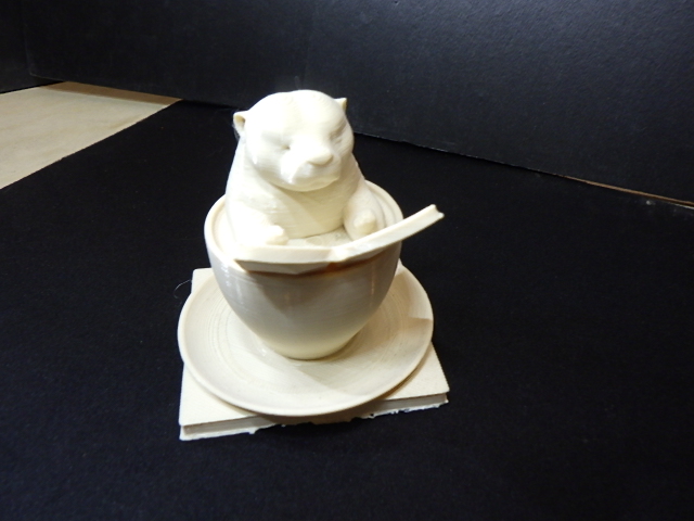A cute otter sitting in a coffee cup reading a book.
